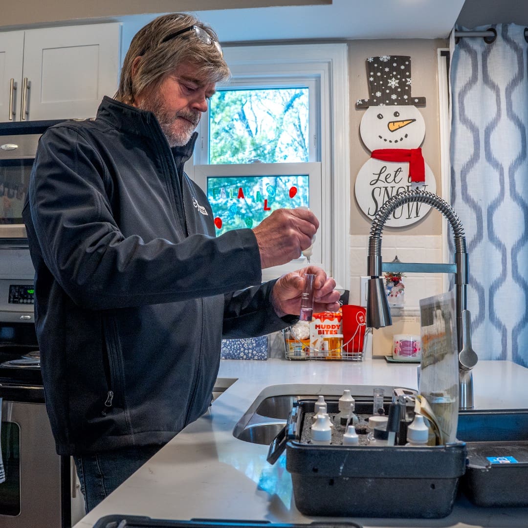 Technician performing a free water test in a customer's kitchen for C and J Water.