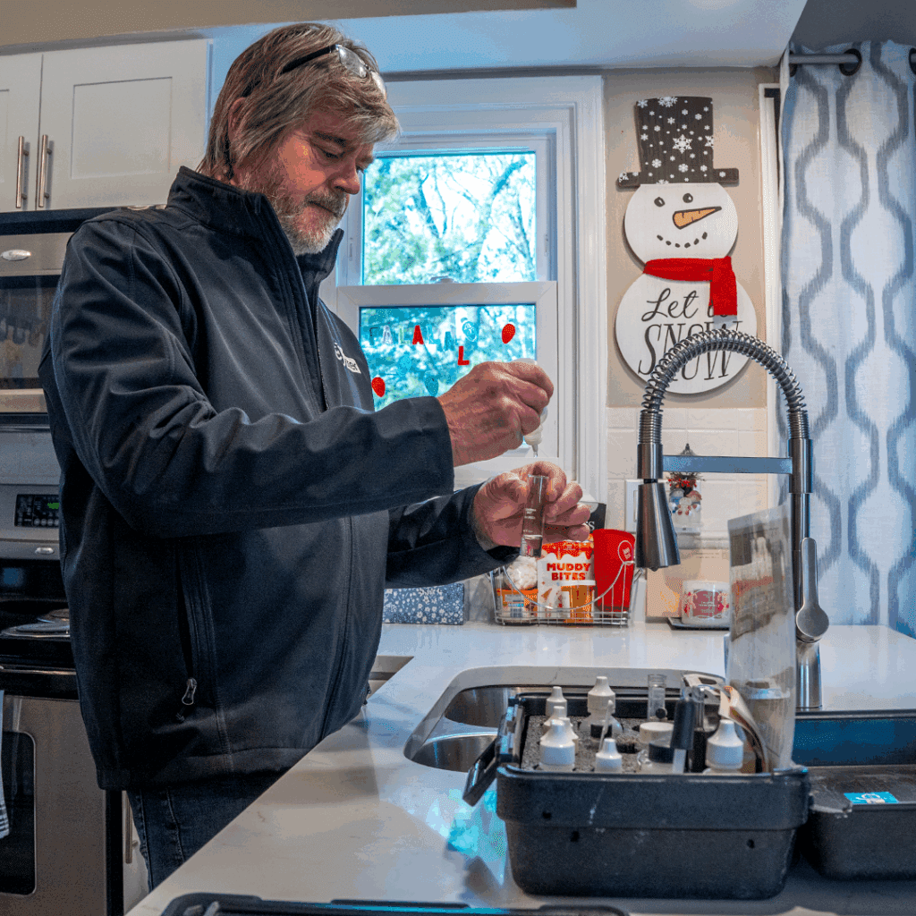 Man testing water at kitchen sink.