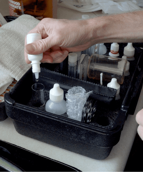 Hand dispensing liquid into small bottles.